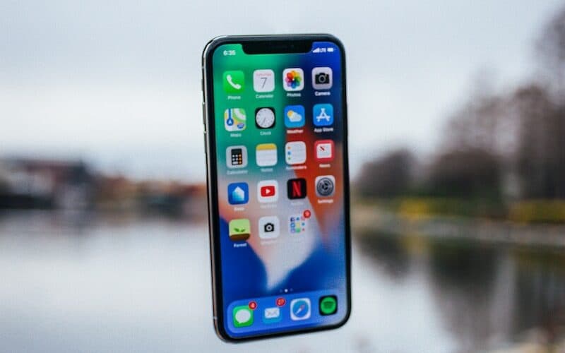 silver iPhone X floating over open palm